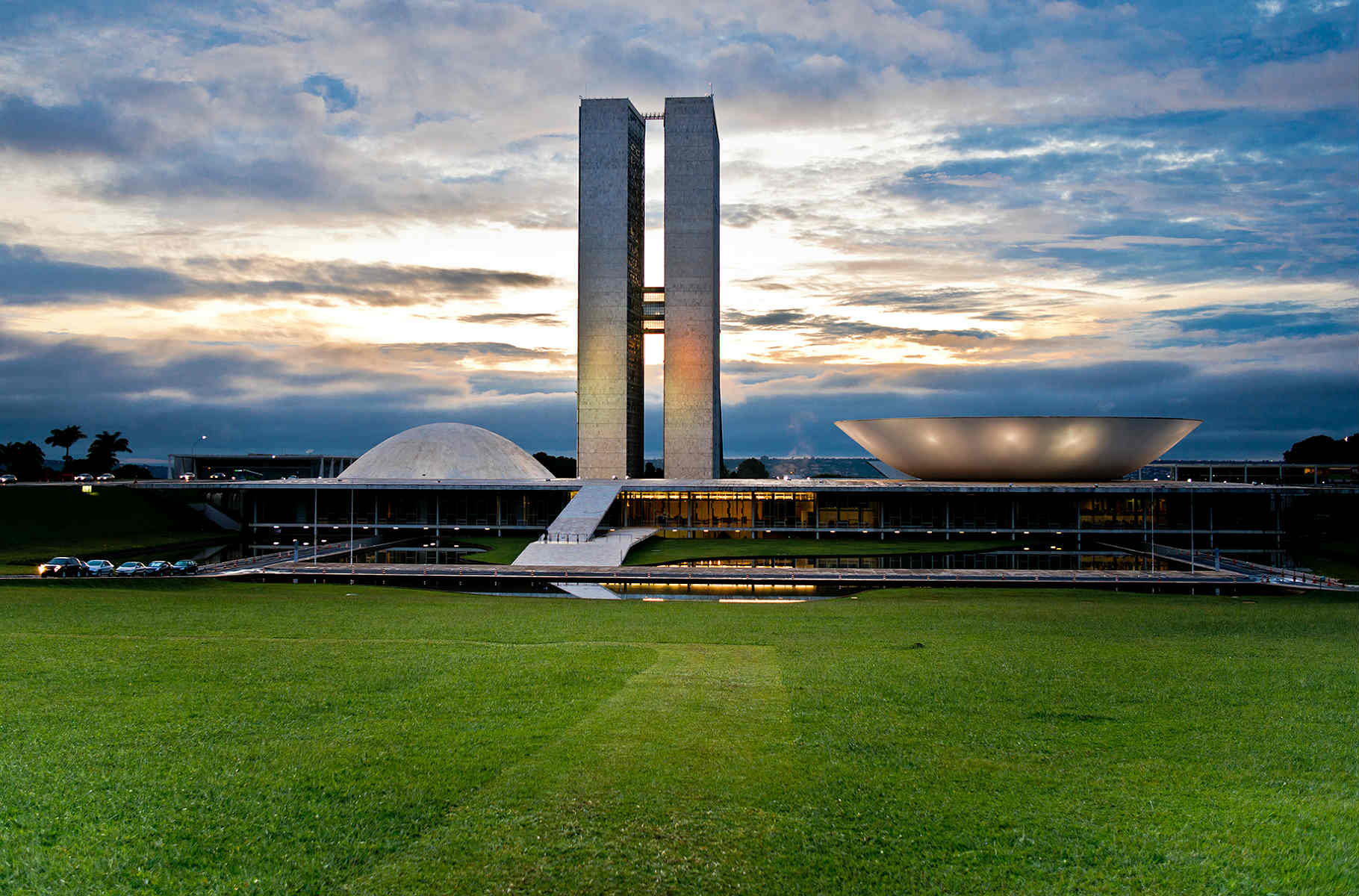 Fachada do Congresso Nacional ao entardecer, vista do gramado do Eixo Monumental em Brasília.