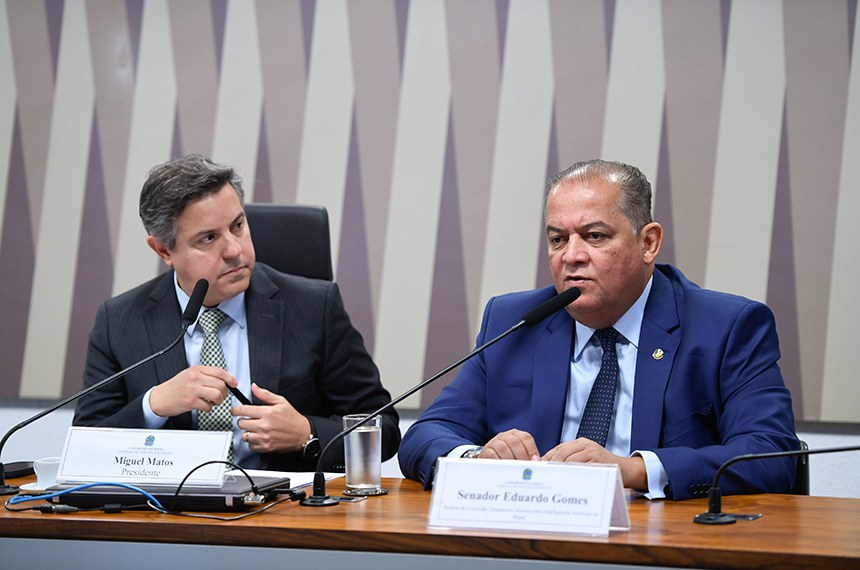 Miguel Matos e o senador Eduardo Gomes lado a lado à mesa de uma audiência no Senado, diante dos microfones.