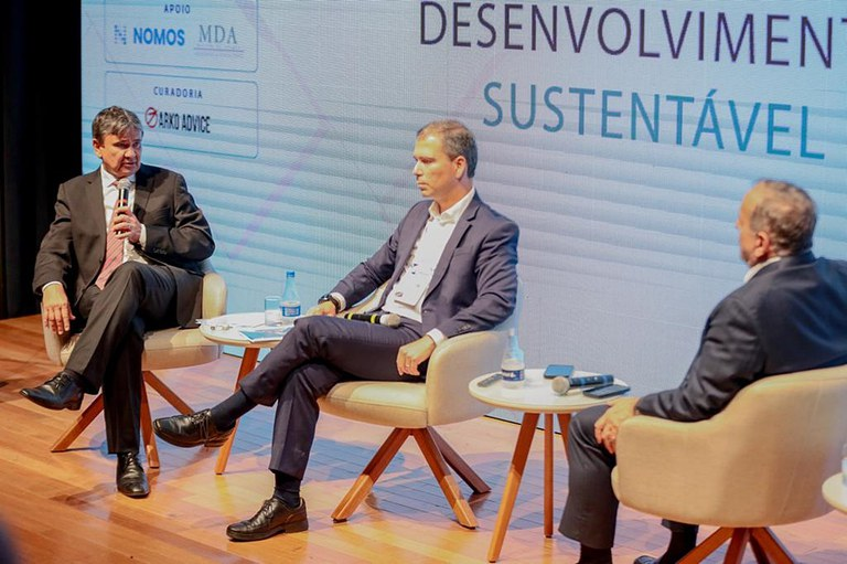Três participantes sentados no palco do Fórum de Brasília debatendo desenvolvimento sustentável.